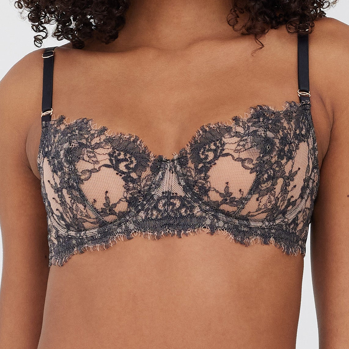 Woman wearing a black lace bra against a neutral background